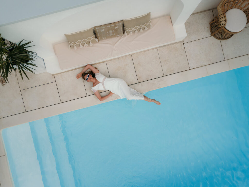 Ein Brautmodel wird aus der Luft gezeigt, wie sie am Pool liegt und hinauf blickt.