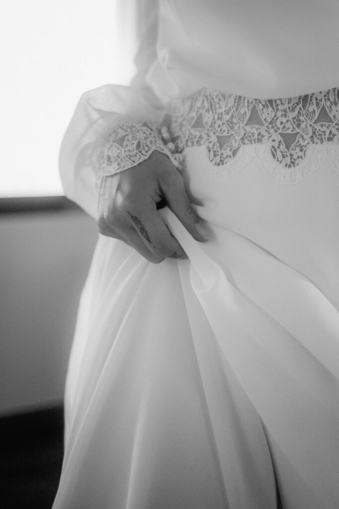 In einem Ausschnitt sieht man, wie die Braut mit einer Hand ihr Kleid hält.