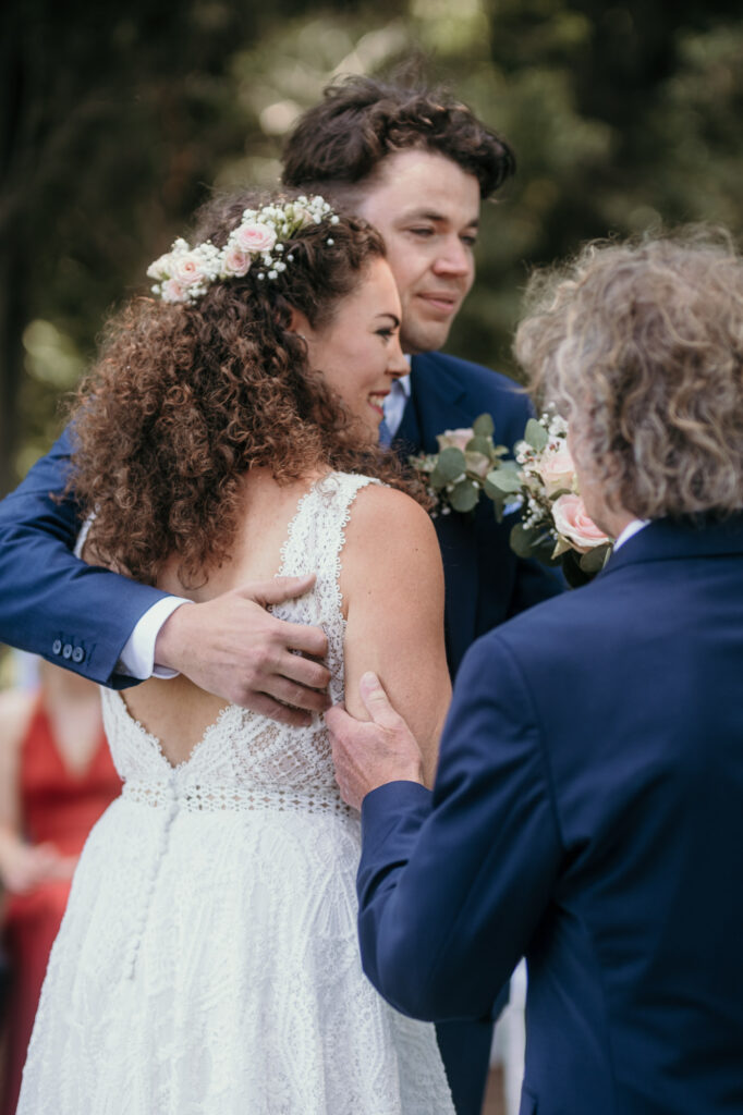 Das Bräutigam nimmt seine Braut glücklich in den Arm, nachdem ihr Vater sie übergeben hat.
