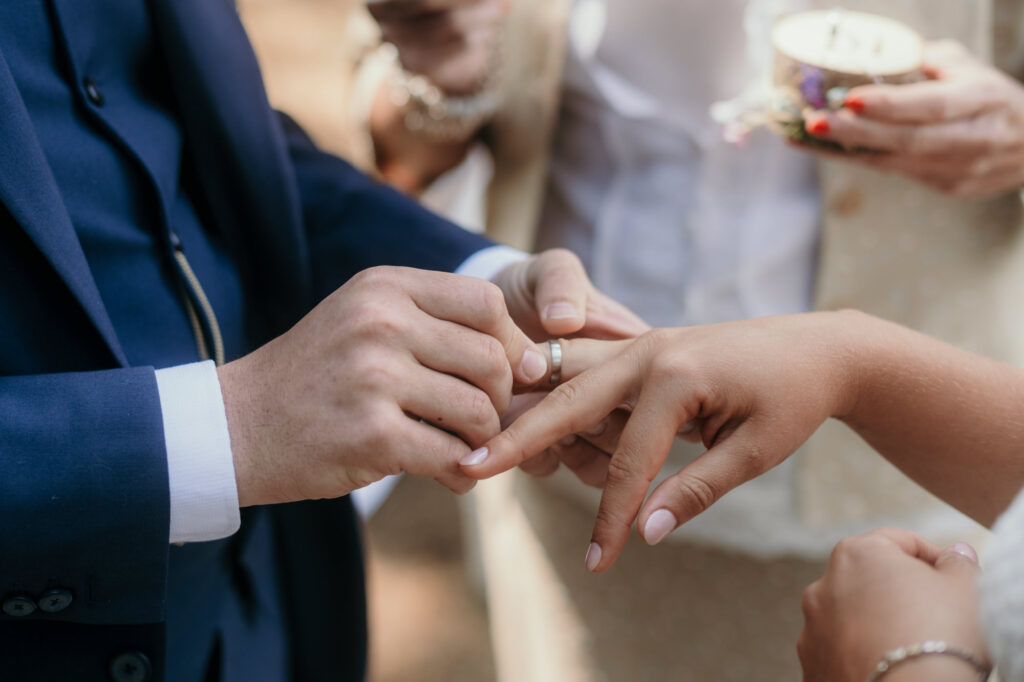 Der Bräutigam steckt seiner Braut den Ehering an den Finger.