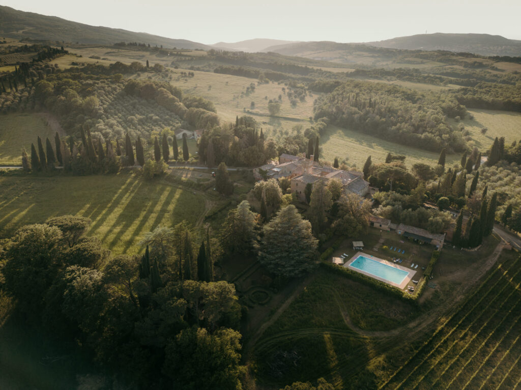 Eine weit entferntes Drohnenfoto zeigt die ganze Anlage einer Hochzeitslocation umgeben von einer grünen Landschaft.