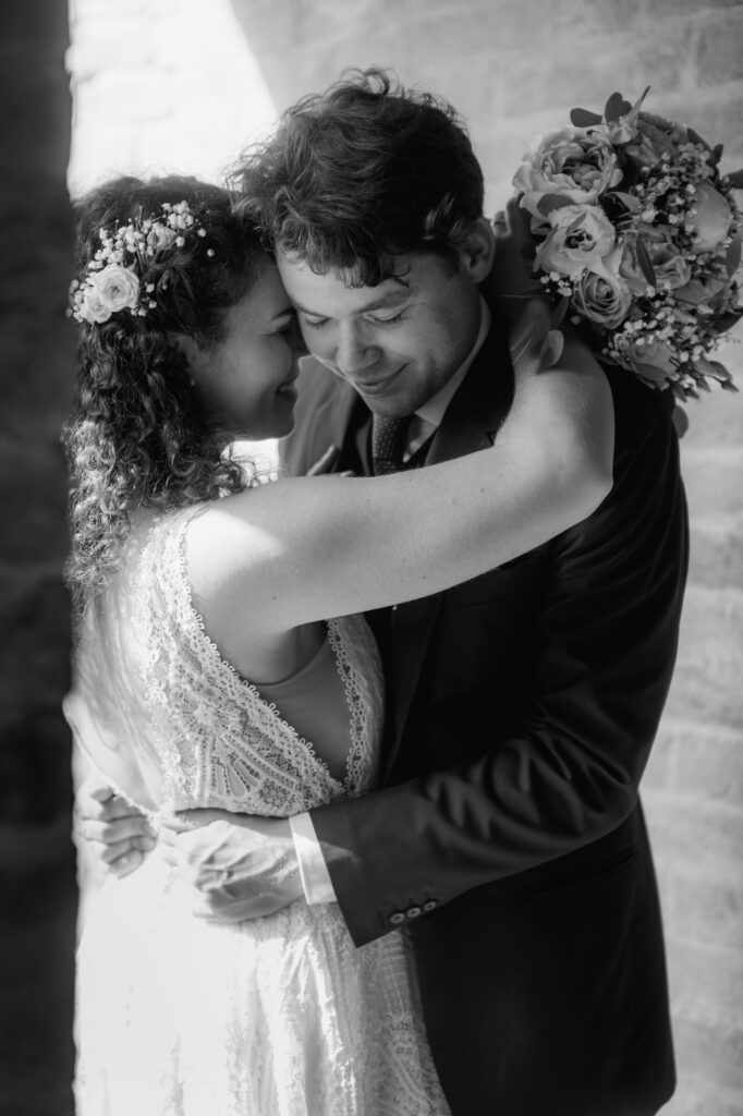 Verliebt umarmt sich das Hochzeitspaar mit geschlossenen Augen und hält die Gesichter aneinander.