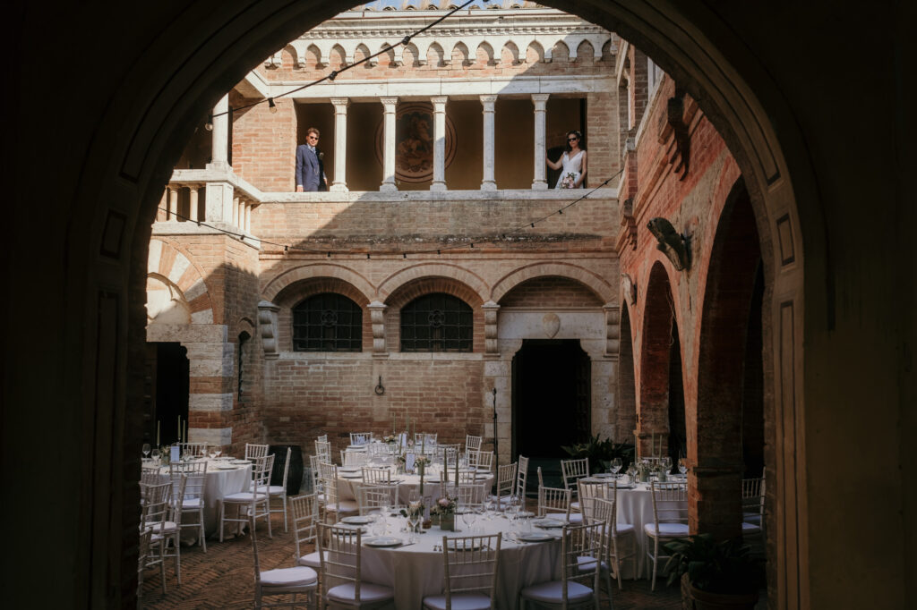 Ein Blick in den Innenhof des Schlosses zeigt die gedeckten Tische. In einem Gang darüber steht das Paar mit etwas Abstand.