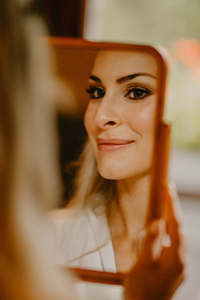 Diese Nahaufnahme zeigt das Spiegelbild der geschminkten Braut in ihrem Handspiegel.