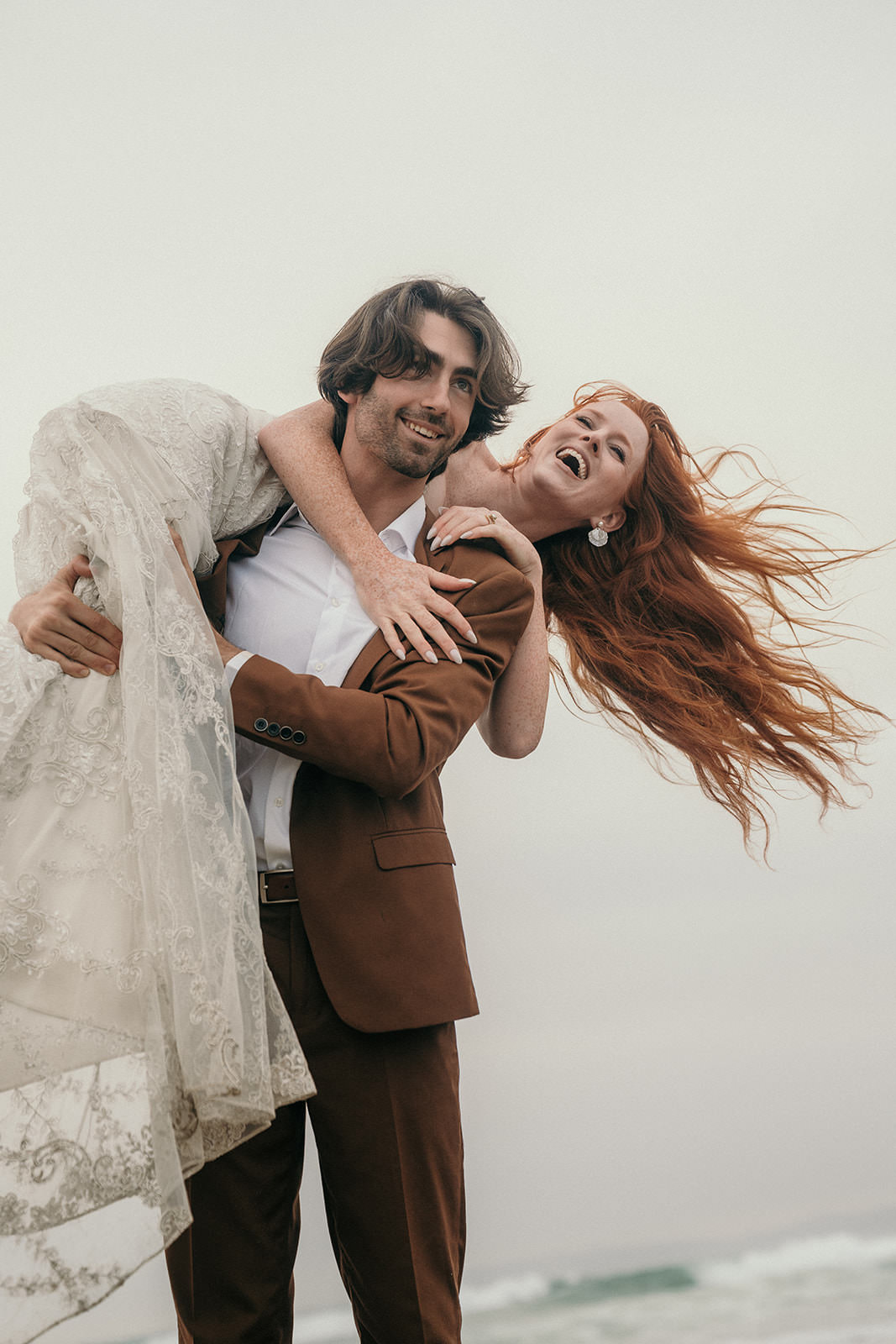 A man has his wife over his shoulders and she is laughing.