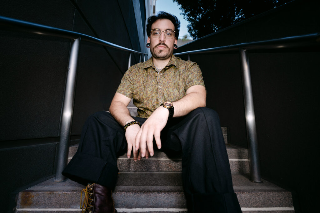 A man sitting on stairs looking straight into the camera.