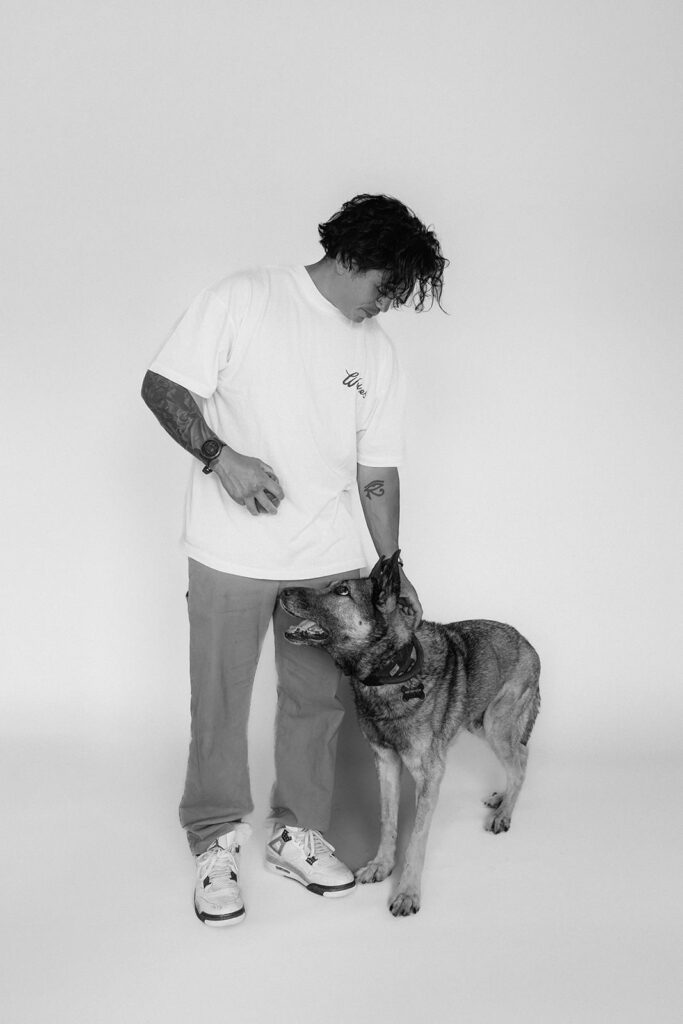 A man standing next to his dog and looking down at him.