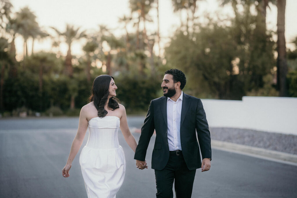 A couple walking towards the camera smiling at each other.
